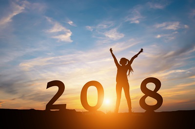 woman creating the 1 in 2018 and sunset in background