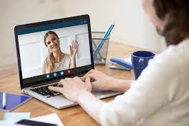 Woman waving from computer screen.